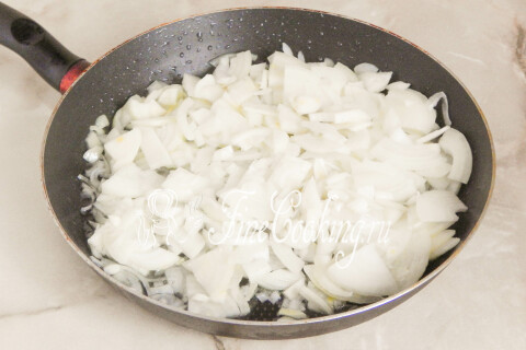 Репчатый лук, нарезанный тонкими полукольцами, на разогретой сковороде.