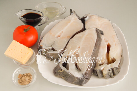 Продукты для стейков зубатки: рыба, помидор, сыр, соевый соус, масло и приправа для рыбы.