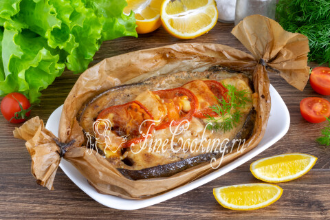 Запечённые стейки зубатки с помидорами и сыром, политые лимонным соком, на тарелке.