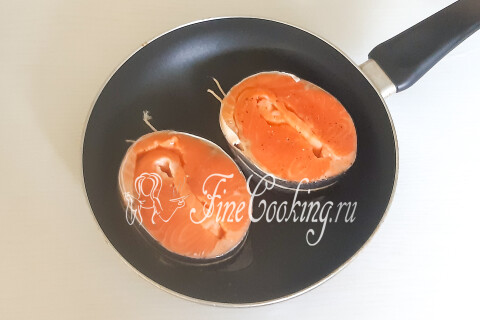 Разогретая сковорода с маслом и уложенными стейками форели.