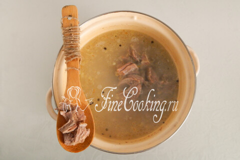 Кусочки говядины в кастрюле супа с рисом и луком