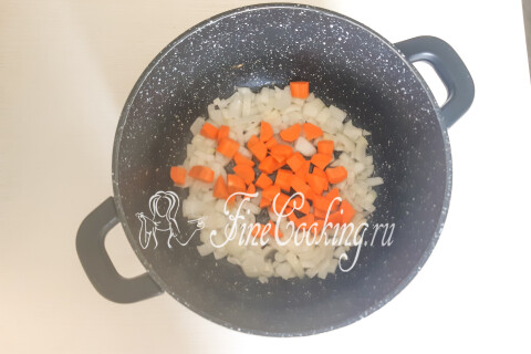 Морковь, нарезанная кусочками, добавленная к обжаренному луку в кастрюле.