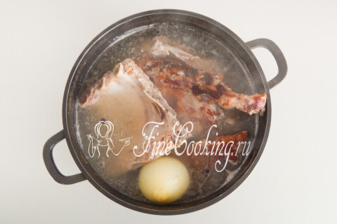 Готовый мясной бульон в кастрюле с разварившимися свиными рёбрами.