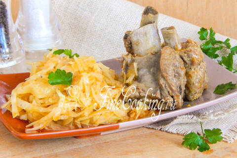 Маринованные огурцы и помидоры рядом с рёбрышками на столе.