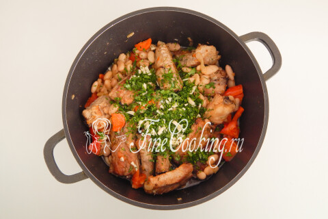 Свиные ребрышки с овощами, зеленью и чесноком в кастрюле под крышкой