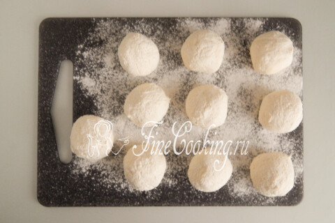 Творожное тесто, разделённое на равные шарики на присыпанной мукой доске.