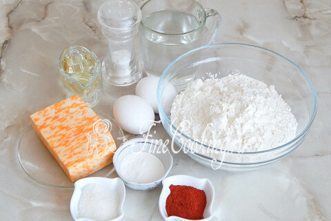 Продукты для сырного хлеба с паприкой: мука, сыр, яйца, вода, масло и специи