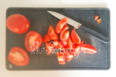 Спелые помидоры на доске, нарезанные небольшими кусочками без плодоножек.