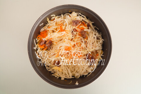 Капуста с тушёнкой и овощами перемешивается лопаткой в чаше мультиварки