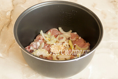 Репчатый лук, нарезанный крупными полукольцами, рядом с мясом.