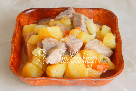 Тушёный картофель с мясом на тарелке со свежими овощами и зеленью