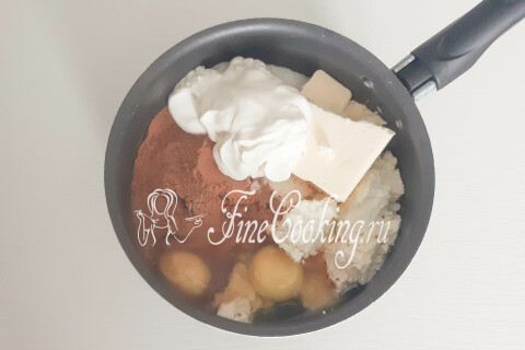 Творог, сахар, масло, сметана, яйца и какао-порошок в кастрюле.