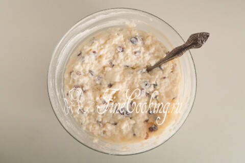Творожная масса с рисом и изюмом, перемешанная ложкой в миске.