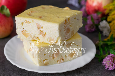 Кусок творожной запеканки с яблоками на тарелке рядом с чаем