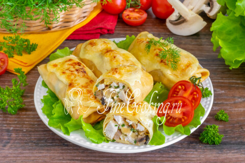 Блинчики яичные с курицей, грибами и сыром поданы горячими на тарелке.