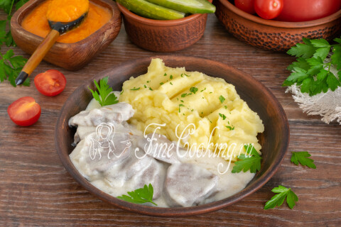 Тарелка с языком в сметане, картофельным пюре и маринованными огурцами