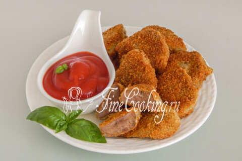 Язык в сухарях на тарелке с соусом и свежей зеленью