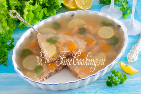 Заливное из рыбы с желатином на блюде — застывшее желе с кусочками форели и лимоном.
