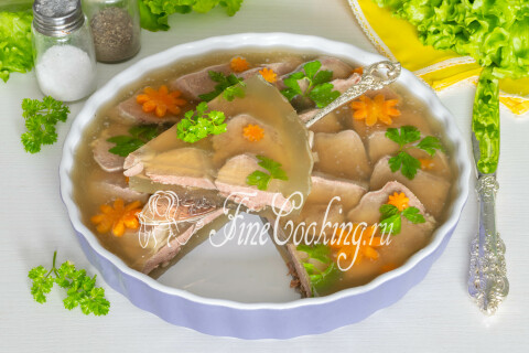 Заливное из языка с ломтиками моркови и зеленью петрушки на блюде.