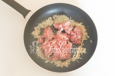 Обжаренный мясной фарш, разбитый лопаткой на мелкие кусочки, в сковороде с луком.