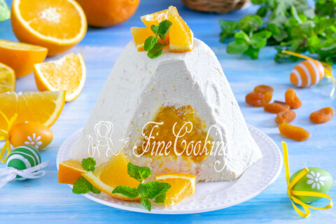 Кусок сырой творожной пасхи с начинкой из кураги и апельсина на тарелке.