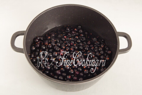 Ягоды чёрной смородины с водой в объёмной кастрюле
